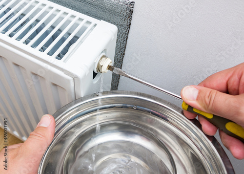 Bleed valve in heating radiator. Hand draining air for adjusts heating system at home. Preparing the house for the new cold autumn or winter season.