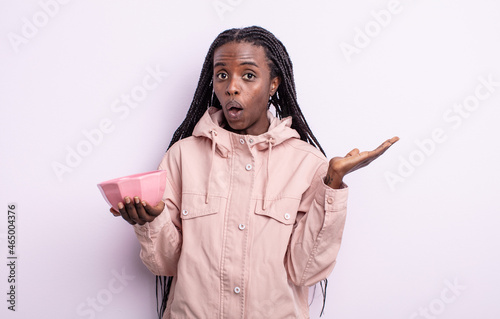 pretty black woman looking surprised and shocked, with jaw dropped holding an object. empty bowl concept photo