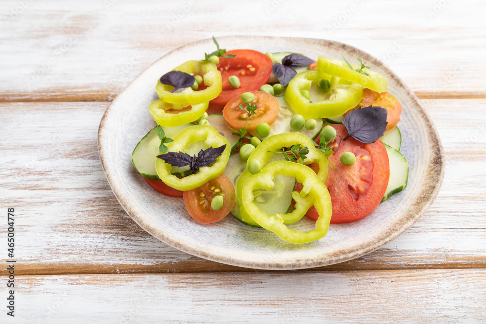 Vegetarian salad from green pea, tomatoes, pepper and basil on white wooden background. Side view. Vegetarian salad from green pea, tomatoes, pepper and basil on white wooden background. Side view.