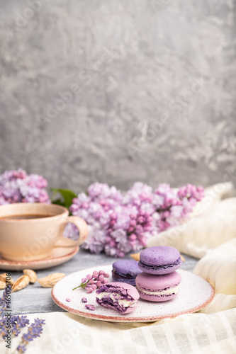Purple macarons or macaroons cakes with cup of coffee on a gray wooden background. Side view, copy space.