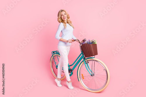 Full size photo of attractive young happy woman go hold bike smile good mood isolated on pink color background © deagreez