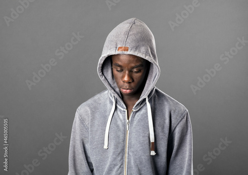 Young Black man wearing a grey hoodie looking down