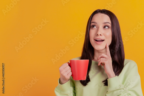 Photo of nice attractive girl drink coffee tea finger touch chin dreamy wondered look empty space isolated on yellow color background