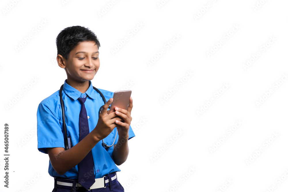 Indian little boy in school uniform with stethoscope and using smartphone on white background. Indian little boy in school uniform with stethoscope and using smartphone on white background.
