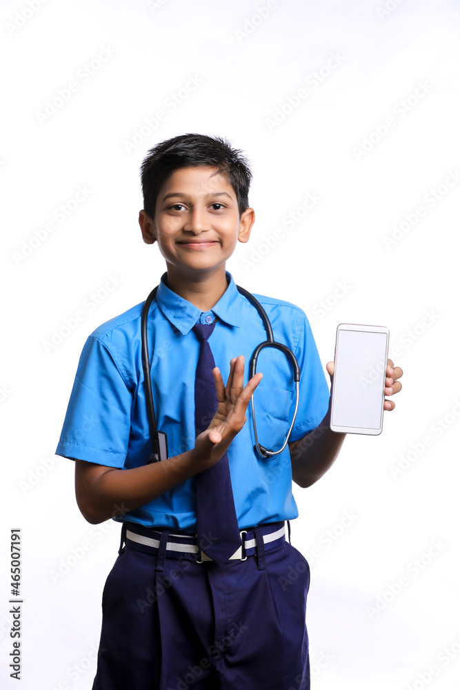 Indian little boy in school uniform with stethoscope and showing smartphone Indian little boy in school uniform with stethoscope and showing smartphone
