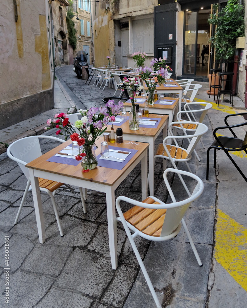Tables mises fleuries dans la rue. Longue terrasse de restaurant dans une rue étroite.