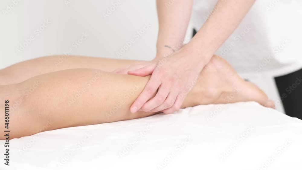Young woman having massage in beauty spa salon, close up. Masseur kneads the foot and leg of young woman Young woman having massage in beauty spa salon, close up. Masseur kneads the foot and leg of young woman