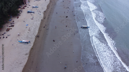 Aerial view of the beautiful Gemah beach with tourists and waves rolling and crashing on the sand photo