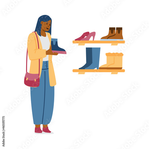 Beautiful African woman stands in front of shelves with shoes in shoe store