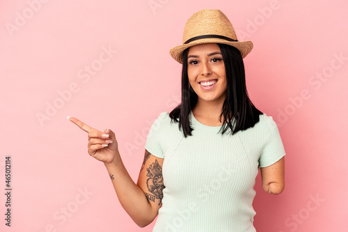 Young caucasian woman with one arm wearing a summer hat isolated on pink background smiling and pointing aside, showing something at blank space.