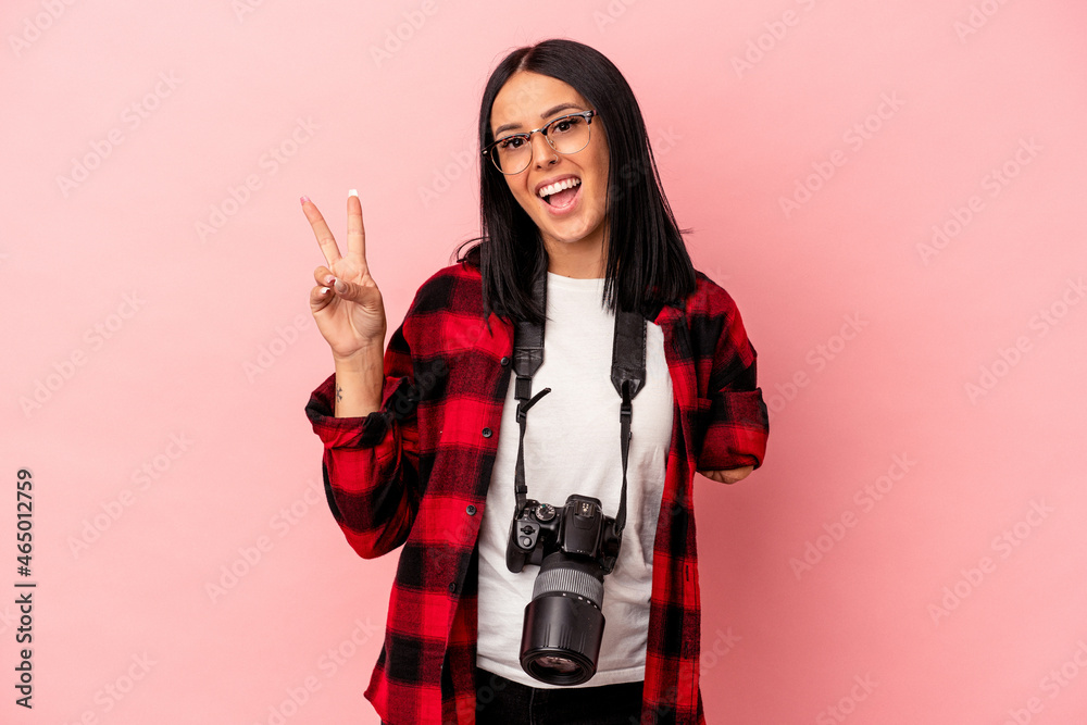 Young caucasian photography woman with one arm isolated on pink background joyful and carefree showing a peace symbol with fingers. Young caucasian photography woman with one arm isolated on pink background joyful and carefree showing a peace symbol with fingers.