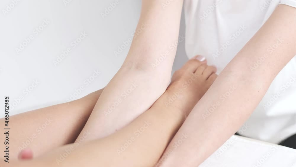 Young woman having massage in beauty spa salon, close up. Masseur kneads the foot and leg of young woman Young woman having massage in beauty spa salon, close up. Masseur kneads the foot and leg of young woman