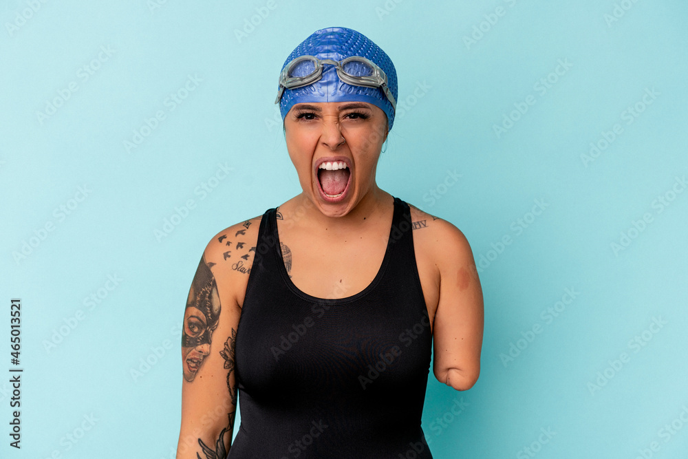 Young swimmer caucasian woman with one arm isolated on blue background screaming very angry and aggressive. Young swimmer caucasian woman with one arm isolated on blue background screaming very angry and aggressive.