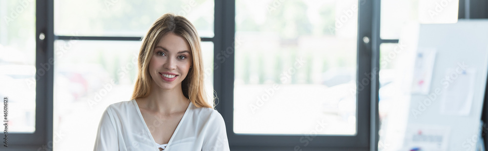 Happy businesswoman looking at camera in office, banner