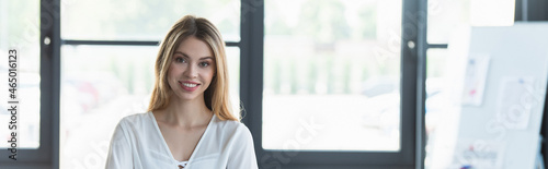 Happy businesswoman looking at camera in office, banner