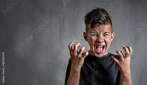 Teen boy screaming in anger on dark background