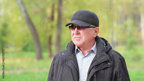 Senior man with a mustache in the park. portrait of a gray-haired man in a shirt and black jacket. © yavdat