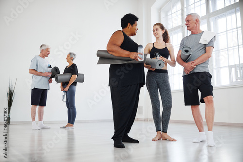 Young instructor giving recommendations to senior people after yoga class in studio