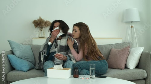 Family compassion. Caring young woman embracing sick wrapped in plaid husband with fever, supporting him during disease
