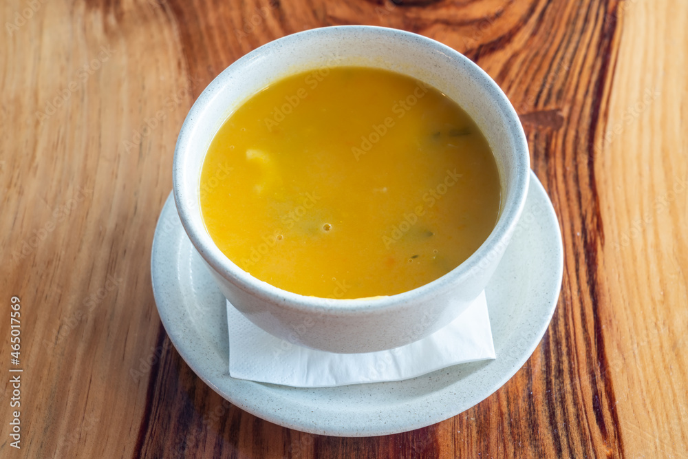 Natural pumpkin, butternut pumpkin soup in a white bowl. On a wooden background. Close up. View from above. Natural pumpkin, butternut pumpkin soup in a white bowl. On a wooden background. Close up. View from above.