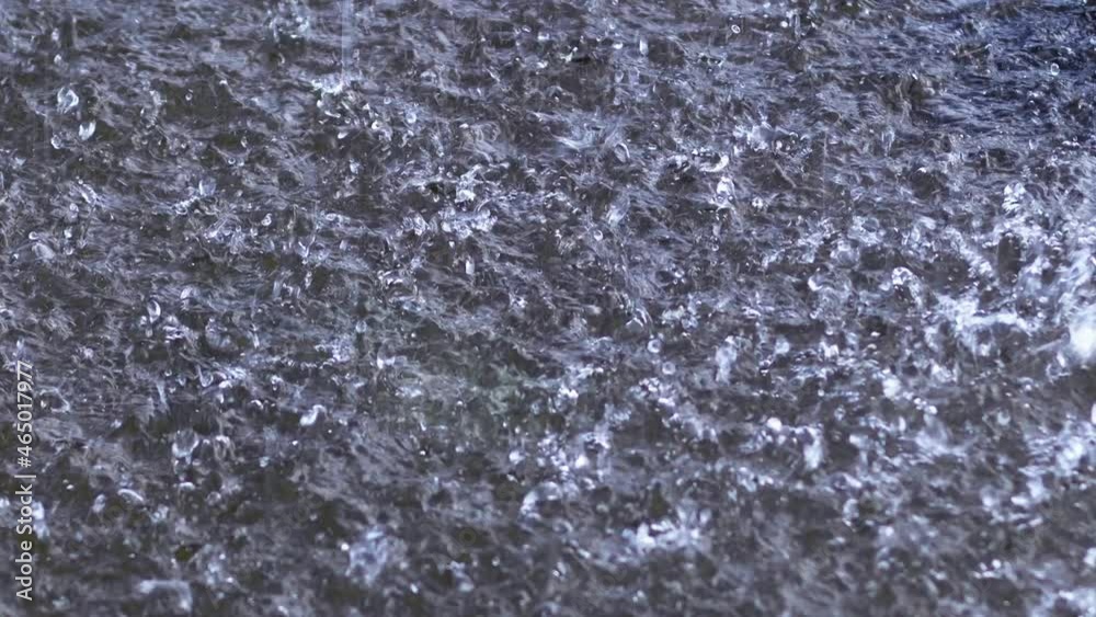 Raindrops fall into a puddle. Slow motion.	
