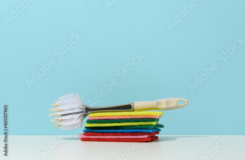 sponge and plastic brush with handle for cleaning the house on a blue background