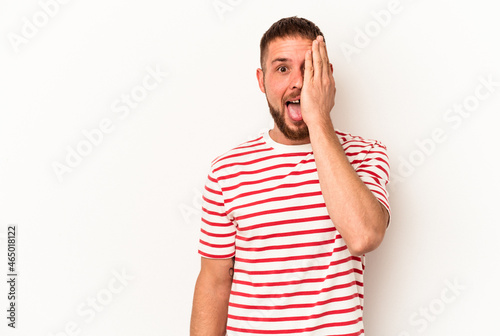 Young caucasian man with diastema isolated on white background having fun covering half of face with palm.
