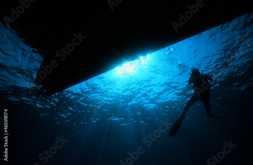 A Scuba Diver Exploring the Ocean Silhouetted by the Sun  with a Dive Boat Shadow Above on a Safety Stop
