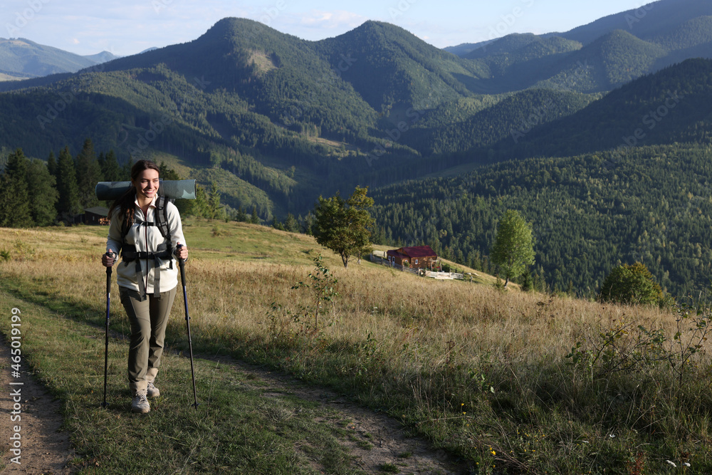 Fototapeta premium Tourist with backpack and trekking poles hiking through mountains, space for text