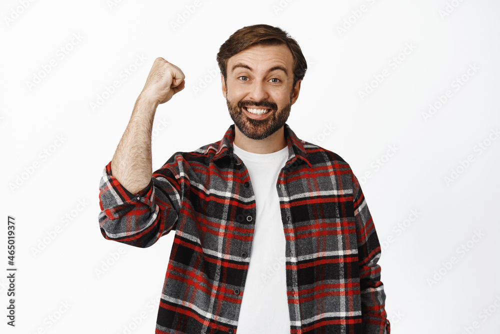 Happy man celebrating, raising clench fist and triumphing, winning and cheering, standing over white background Happy man celebrating, raising clench fist and triumphing, winning and cheering, standing over white background
