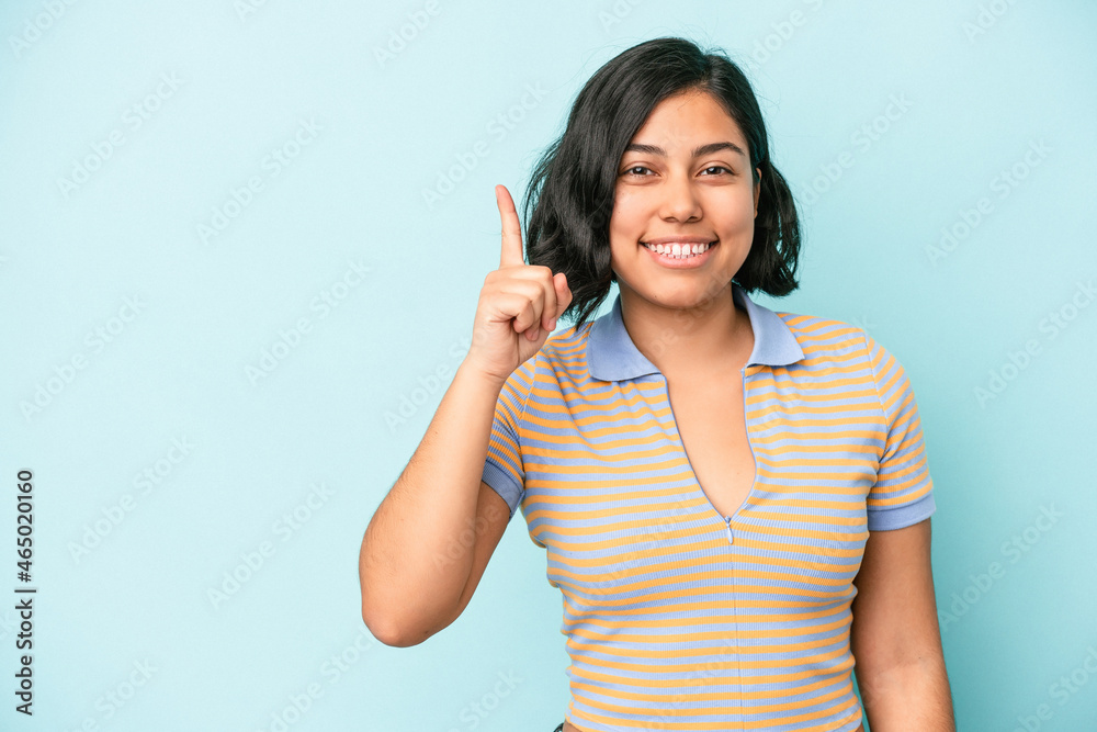 Young latin woman isolated on blue background showing number one with finger. Young latin woman isolated on blue background showing number one with finger.