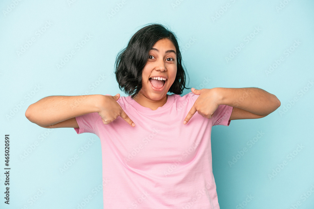 Young latin woman isolated on blue background surprised pointing with finger, smiling broadly. Young latin woman isolated on blue background surprised pointing with finger, smiling broadly.