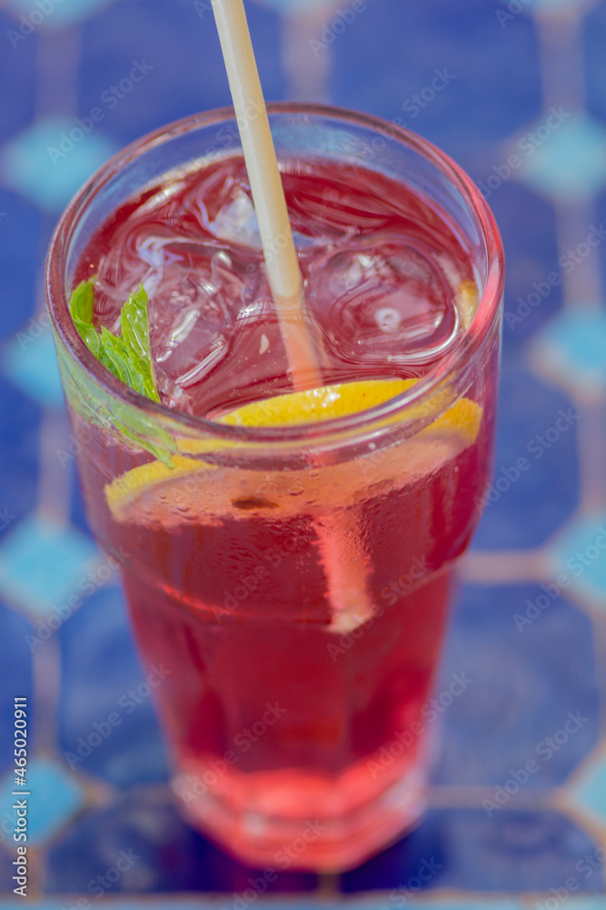 Close up of a colorful cold beverage, with a slice of lemon and a basil leaf Close up of a colorful cold beverage, with a slice of lemon and a basil leaf