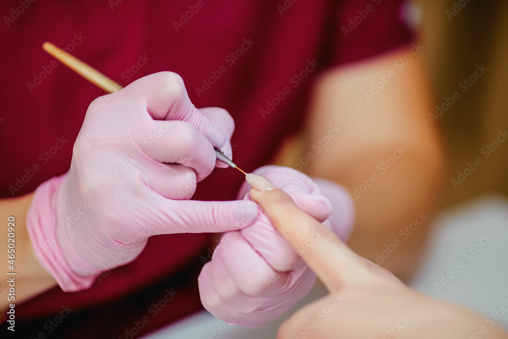 Fine brush manicure nail polish, nail polish, modeling gel. A woman gets a manicure in the salon. Fine brush manicure nail polish, nail polish, modeling gel. A woman gets a manicure in the salon.