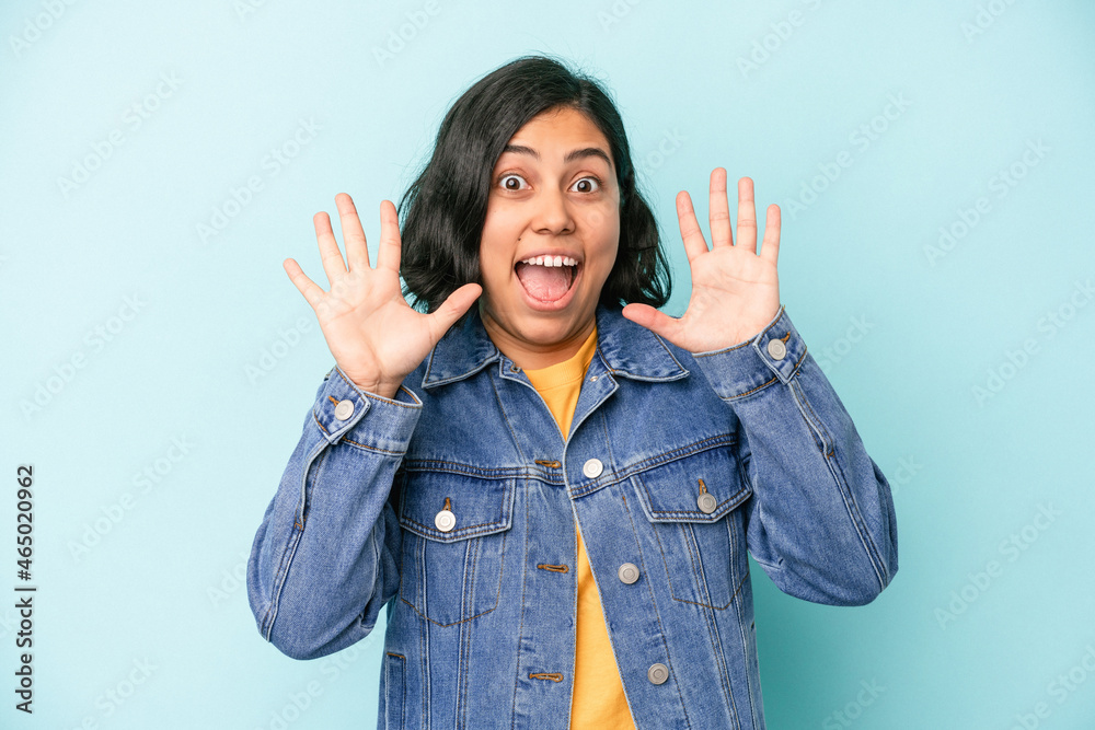 Young latin woman isolated on blue background receiving a pleasant surprise, excited and raising hands. Young latin woman isolated on blue background receiving a pleasant surprise, excited and raising hands.