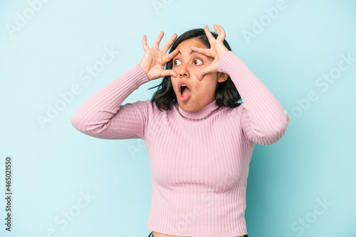 Young latin woman isolated on blue background keeping eyes opened to find a success opportunity.