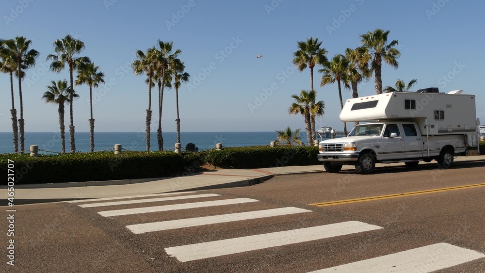 Motorhome trailer or caravan for road trip. Waterfront tropical palm trees and pacific ocean beach, Oceanside California USA. Beachfront vacations in camper van, RV motor home. Mobile home campervan.