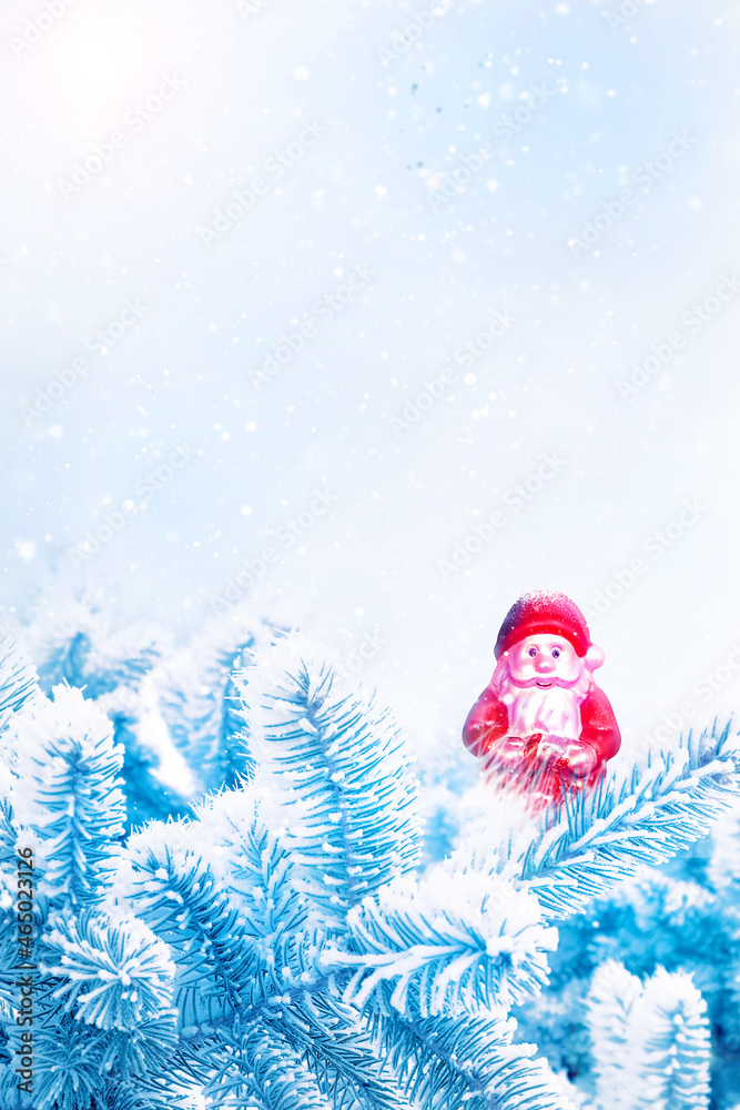 Christmas card. Toy Santa in fir snow branches. Winter snowy background. Banner format.