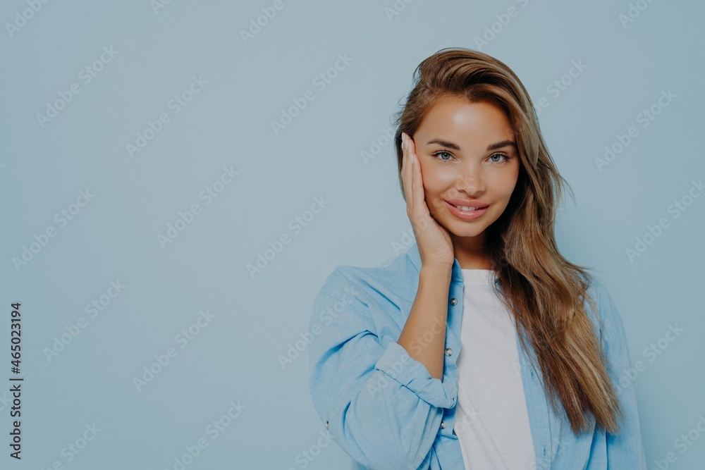 Positive woman smiling at camera on light blue background Positive woman smiling at camera on light blue background