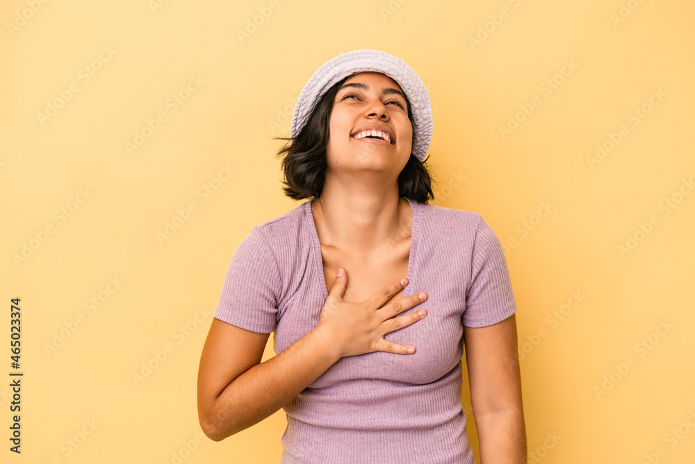Young latin woman isolated on yellow background laughs out loudly keeping hand on chest. Young latin woman isolated on yellow background laughs out loudly keeping hand on chest.