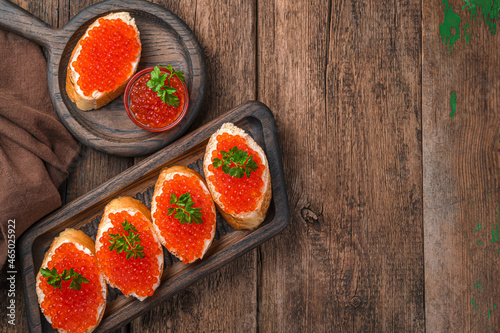 Sandwiches with red caviar on a wooden background. Top view, copy space.