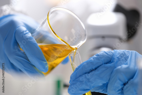 Tableau sur toile Gloved hands pour liquid biofuel into a flask