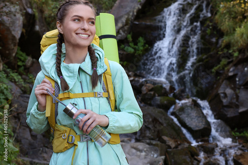 Tourist with backpack and bottle near waterfall in mountains. Space for text © New Africa