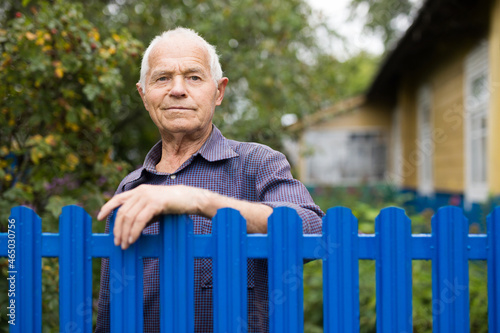 Old man standing beside fence