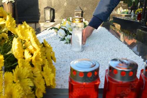 Man putting a white votive candle on the grave photo