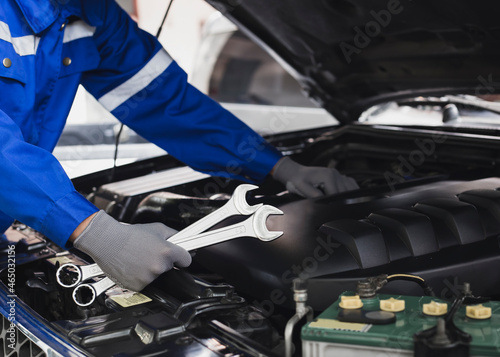 Mechanic works on the engine of the car in the garage.Concept of car inspection service and car repair service.