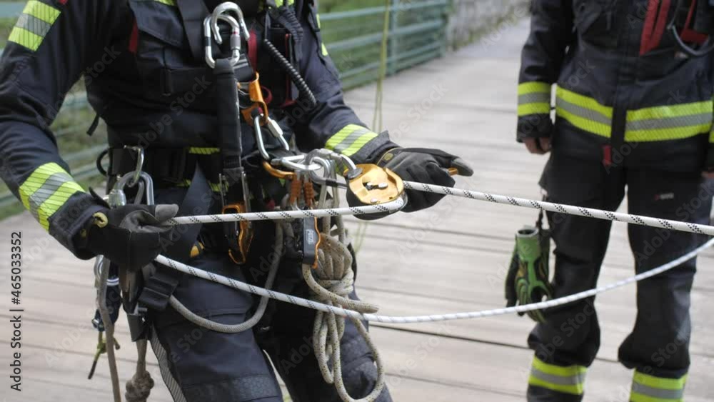 fireman tests rope and pulley before descending from bridge, medium slow motion shot fireman tests rope and pulley before descending from bridge, medium slow motion shot