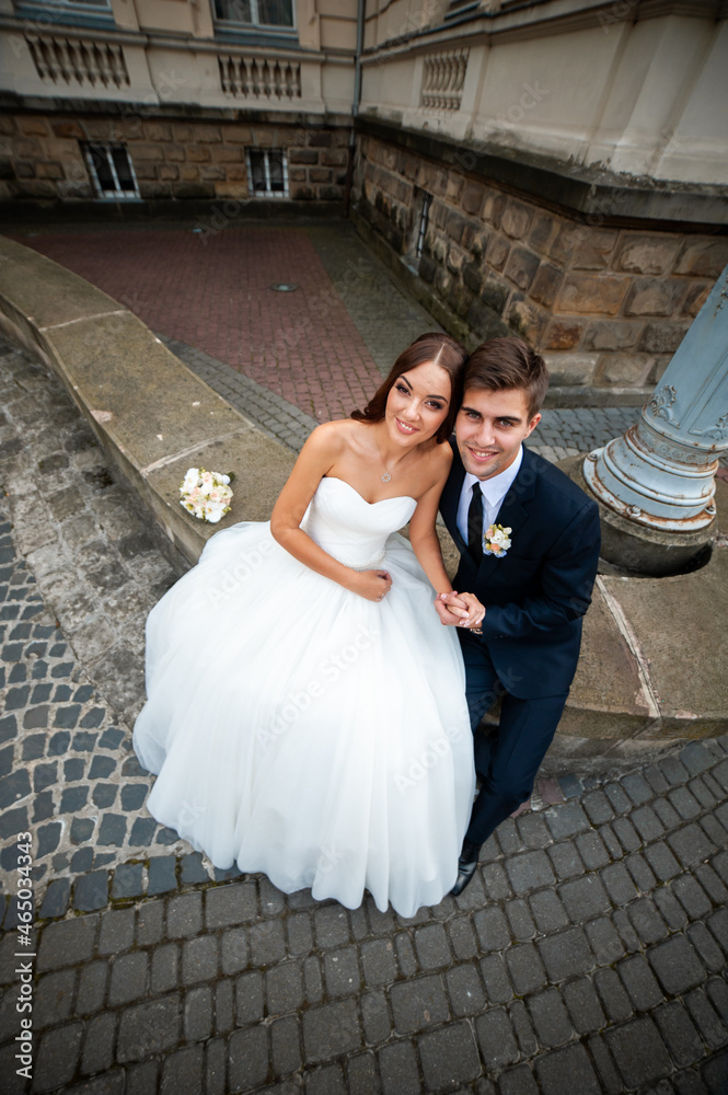 Beautiful young bride with wedding bouquet and groom near old castle before wedding ceremony Beautiful young bride with wedding bouquet and groom near old castle before wedding ceremony