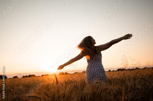Peaceful woman wellcoming the rising sun in field photo