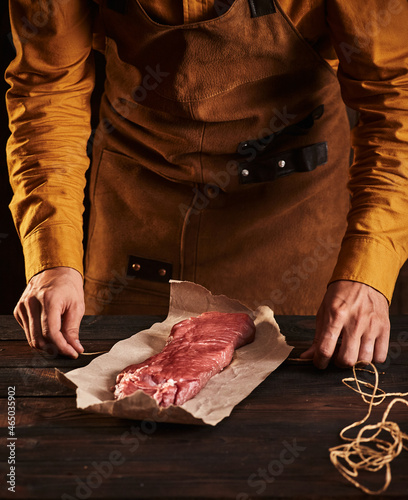 The butcher wraps a piece of meat in paper.